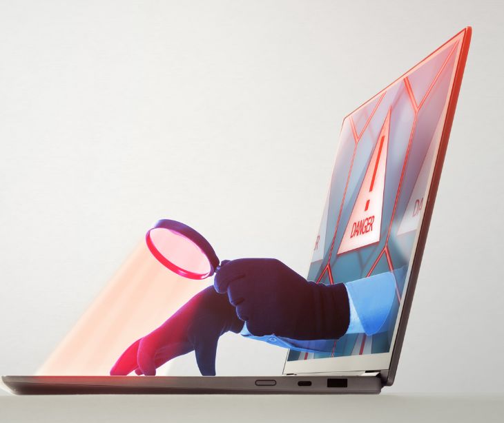 hands coming out of laptop screen holding a magnifying glass