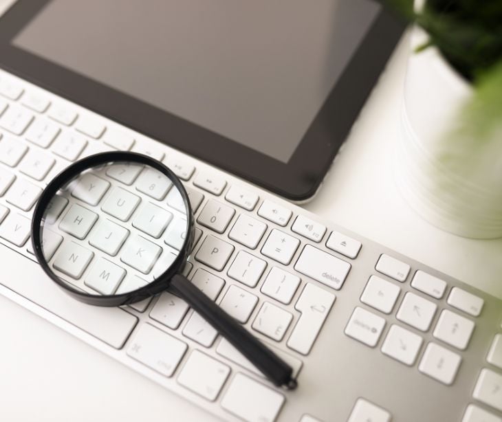 magnifying glass on a keyboard with tablet