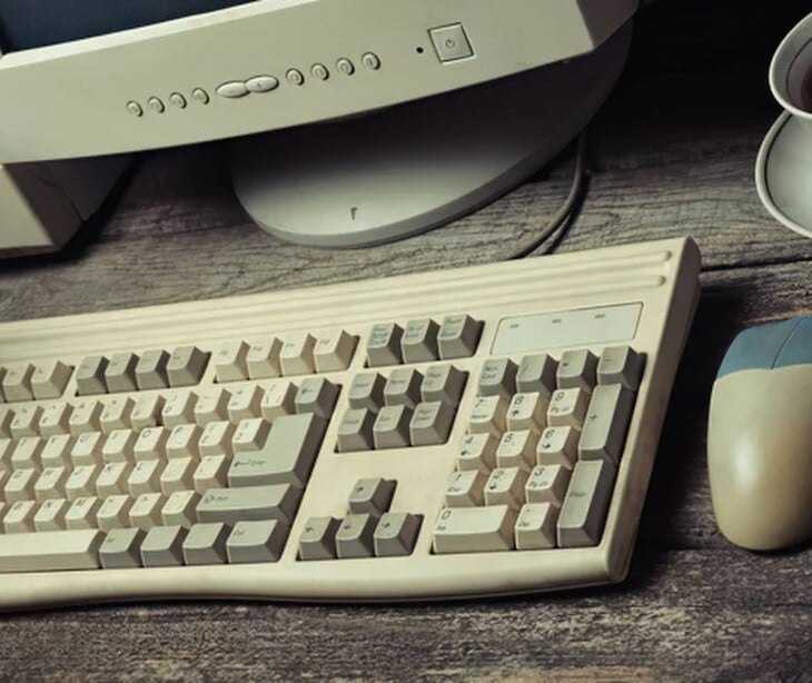 Image of an outdated keyboard and computer. 