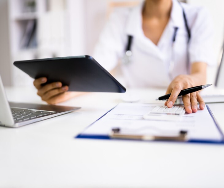Image of a practicioner reviewing notes with a laptop and tablet nearby. 