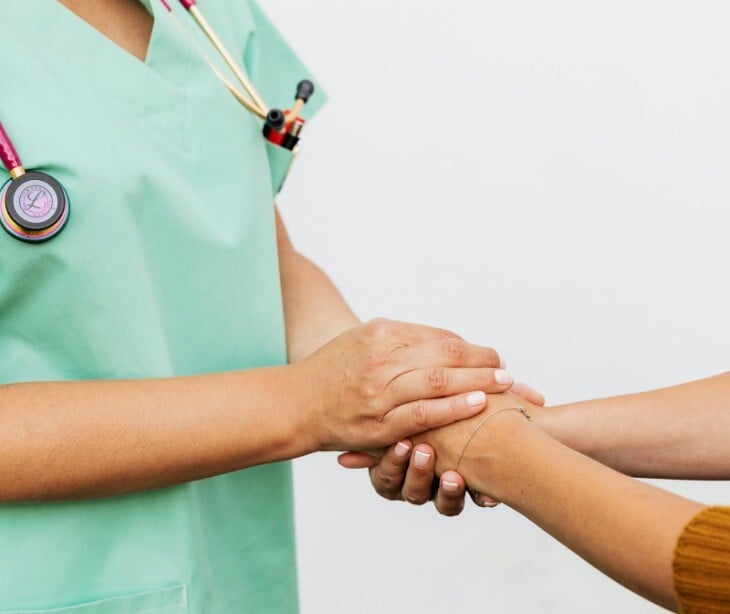 Image of a provider holding the hands of a patient. 