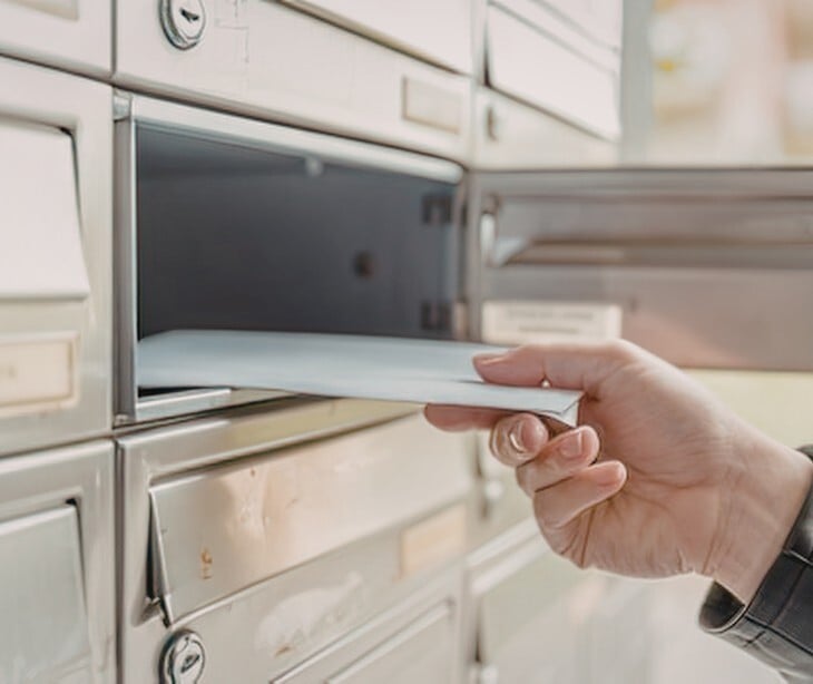 Image of someone placing an envelope in a mailbox. 