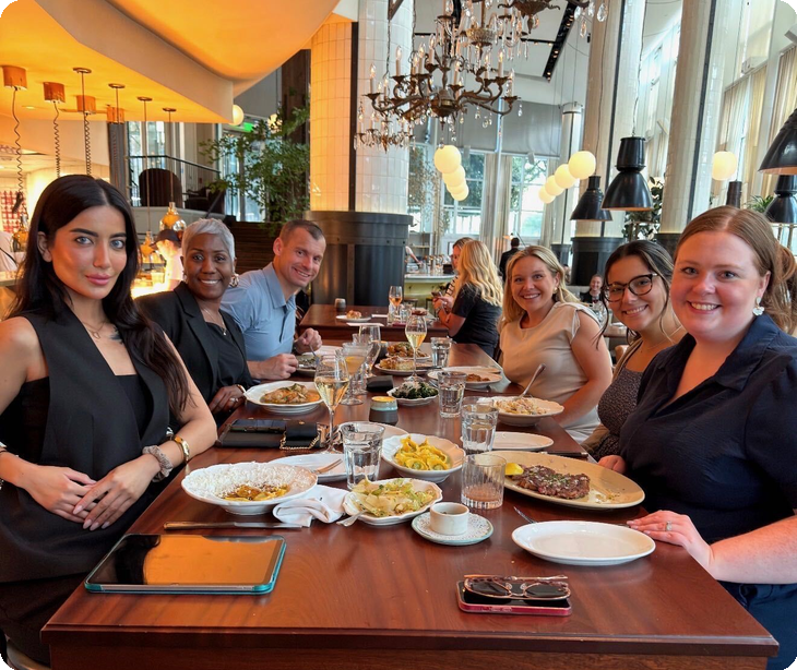 Six guests at a long table at St. Cecilia in Atlanta during a Paubox Table dinner, with shared plates down the center of the table